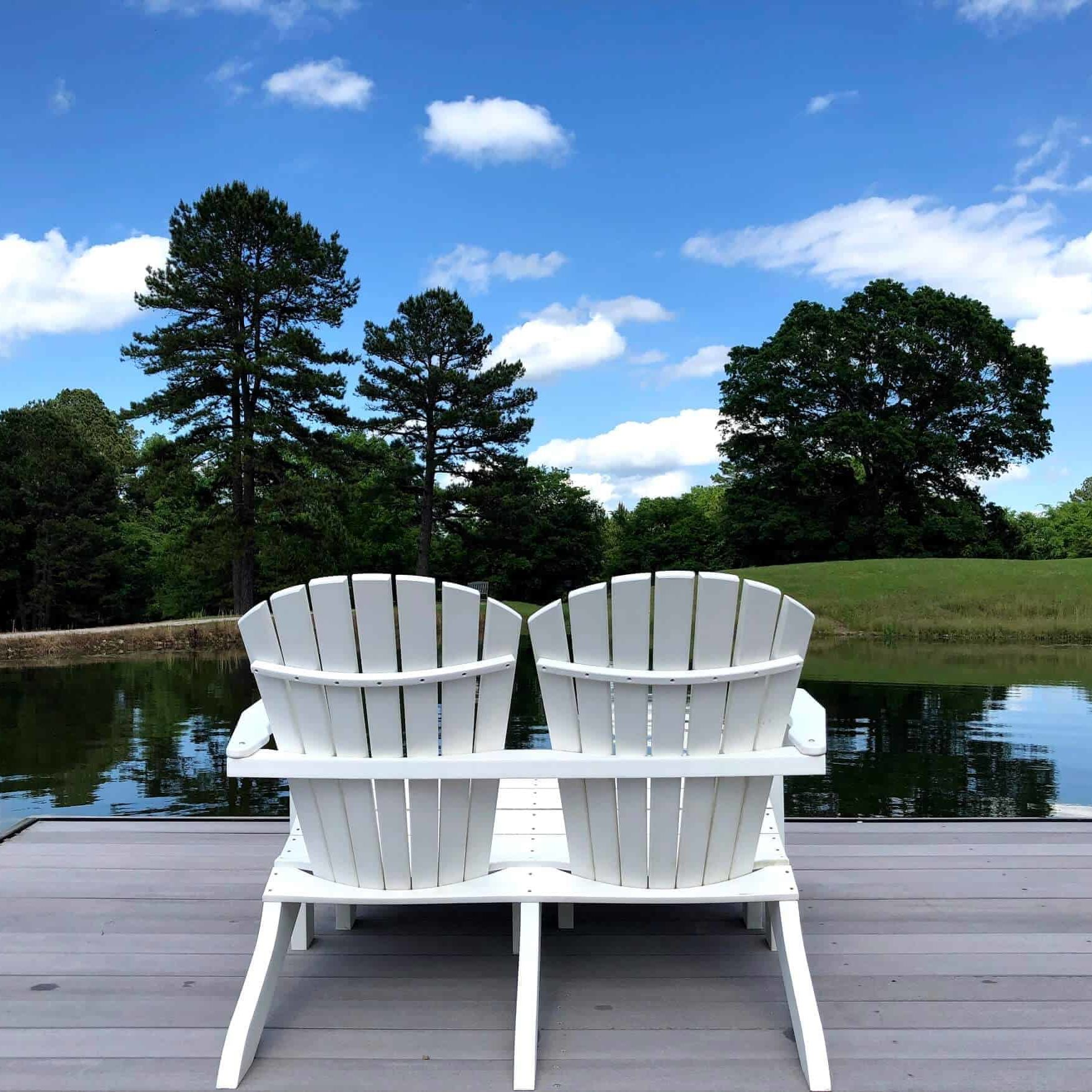 Two chairs on a dock overlooking a pond